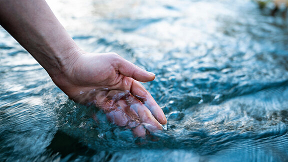 A female hand touching the river water
